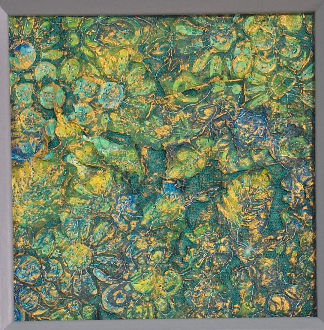 A textured mixed media artwork featuring a variety of fabrics and colors including blue, green, and gold.