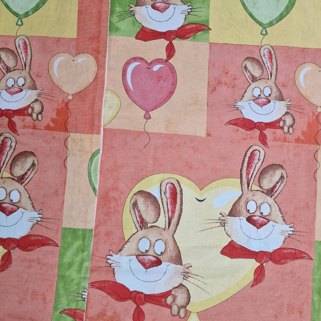 Cotton fabric with a pattern featuring cartoonish rabbits, balloons, and hearts in a colorful, child-friendly design.