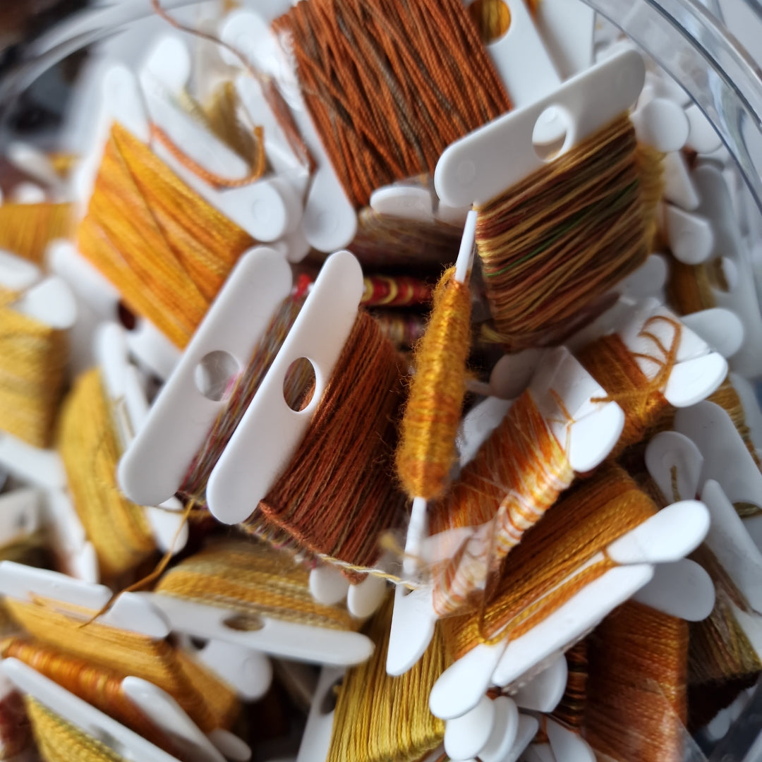 Close-up of spools of thread in a glass jar
