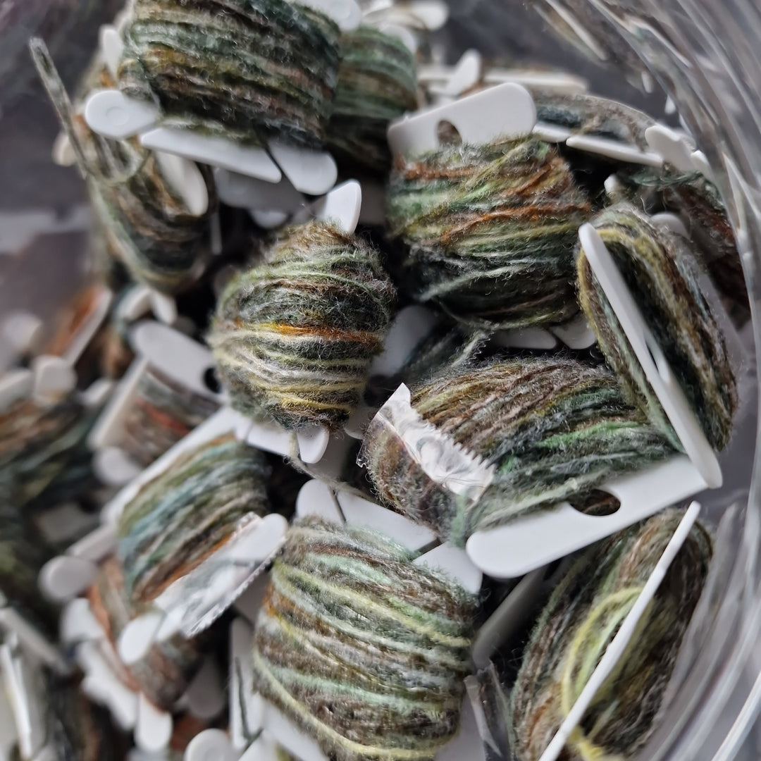 Close-up of yarn on white spools in a clear container
